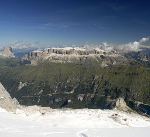 Pohled z vrcholového hřebene na Sassolungo, masiv Sella a horu Piz Boe a jezero Lago di Fedaia